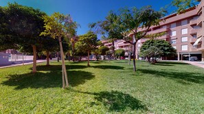Guests can enjoy shaded relaxation in this tranquil outdoor area surrounded by trees and overlooking a multi-story building with balconies.