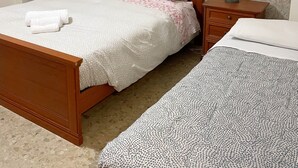 A bedroom with a wooden bed, two bedside tables, a nightstand, and a patterned wall.