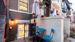 A small patio with a table and chairs, a lamp, and a potted plant. - Sojourn in DuPont Circle: Modern Meets Historic (Washington)