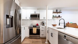 A modern kitchen with white cabinets, stainless steel appliances, and a wooden floor. - Sojourn in DuPont Circle: Modern Meets Historic (Washington)