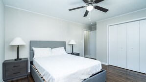 Ein Schlafzimmer mit einem Bett, zwei Nachttischen mit Lampen, einem Deckenventilator und einem Kleiderschrank.