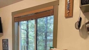 Een keuken met een houten aanrecht, een raam met uitzicht op bomen en een bord aan de muur.
