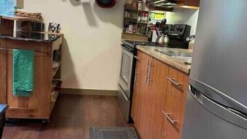 Cocina compacta con armarios de madera, microondas, estufa y refrigerador.