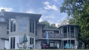 A two-story house with a balcony and a covered patio area. - Spacious multi-level lakeside home w/ renovated kitchen and abundant parking!  (Penn Yan)