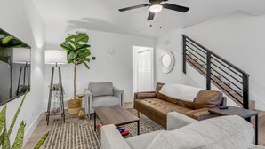 A modern living room with a sofa, armchair, coffee table, and a large plant. - Modern Townhome w/ Deck and Fast Wifi 7 min from AT&T Stadium  (Arlington)