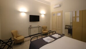 Une chambre d’hôtel comprenant un lit, deux fauteuils, une télévision et une armoire.
