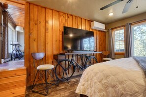 L’intérieur d’un chalet en bois, avec un lit, un téléviseur, un vélo et une table à manger.