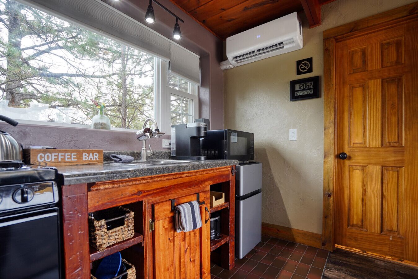 A kitchen with a coffee bar sign, a microwave, a refrigerator, a stove, and a wooden door.