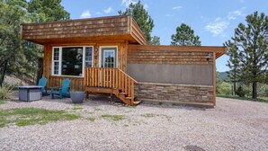 Eine Holzhütte mit Veranda, zwei blauen Stühlen und einem Tisch.