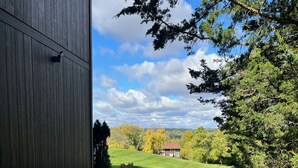 Ein Weg führt zu einem Gebäude mit Holzfassade, umgeben von Kies und blühenden Pflanzen.