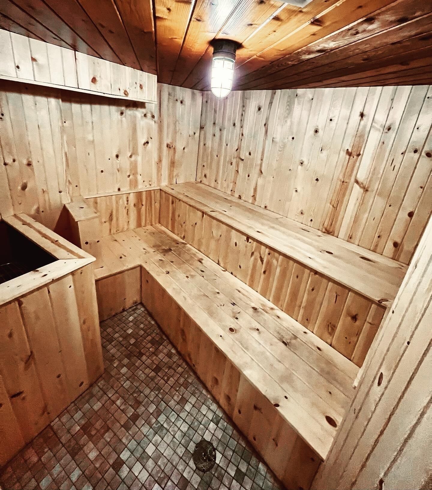A wooden sauna with benches and a tiled floor.