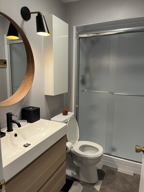 A modern bathroom with a white sink, black faucet, and a round mirror. - 
Newly Updated Modern, Spacious, and Cozy Condo- Right on the Lake! (Lake Geneva)