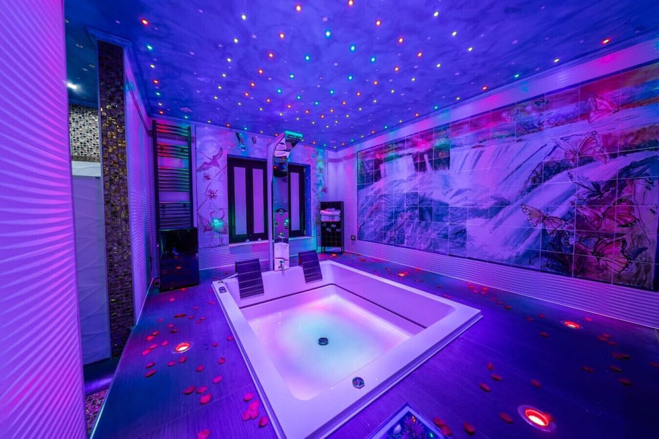 Ein moderner Wellnessraum mit einer großen Badewanne, stimmungsvoller Beleuchtung und Wandmalerei.