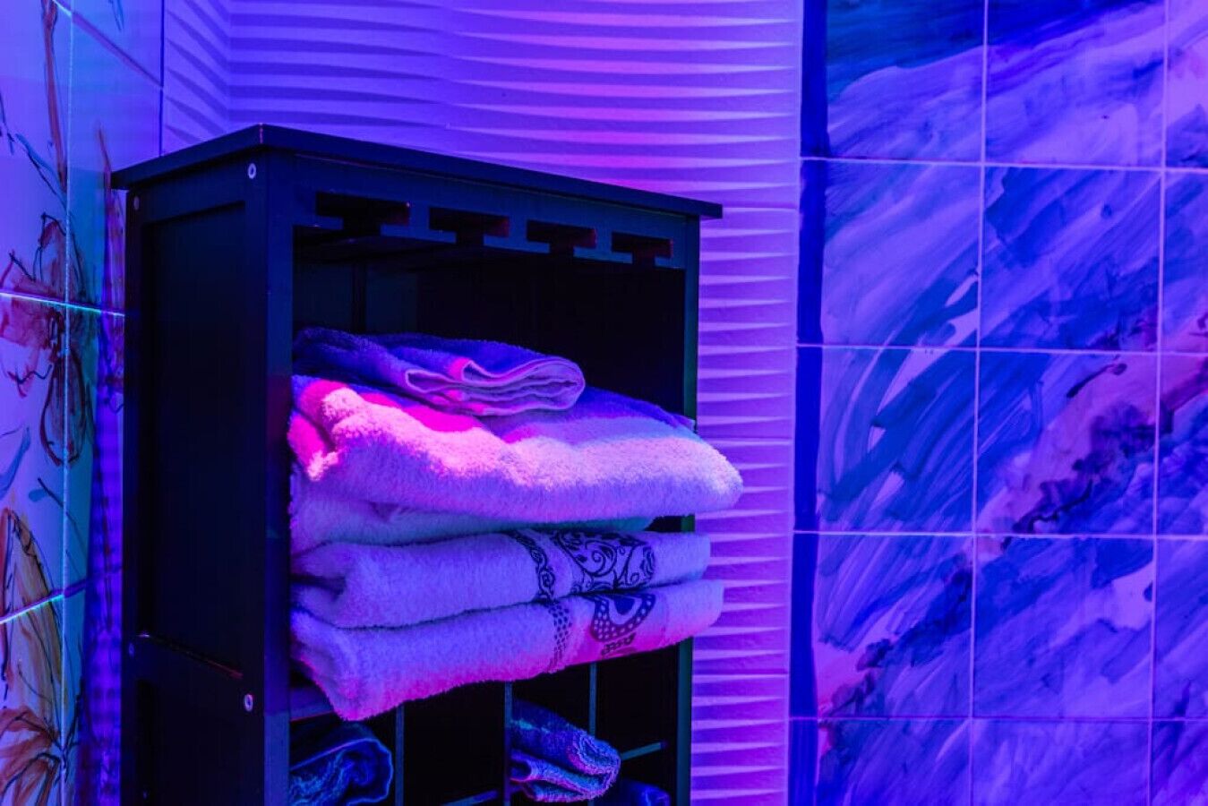 Une salle de bain avec un porte-serviettes où sont pliées des serviettes et un mur décoratif orné d’un motif ondulé.