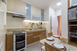 A modern kitchen with a built-in oven, a dining area with a table set for two, and a microwave above the counter.
