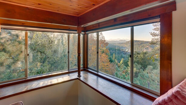 A room with large windows offering a view of a forested area and mountains. - Crestline Cabin: Mountain Views & Fire Pit! (Crestline)