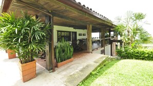 A covered outdoor area with a concrete floor, potted plants, and a wooden structure with a tiled roof. - CASA HOTEL MÁLAGA (Montenegro)