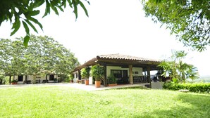 A building with a tiled roof, surrounded by a well-maintained lawn and various potted plants. - CASA HOTEL MÁLAGA (Montenegro)