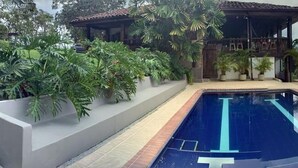 A swimming pool with clear blue water, surrounded by a patio area with outdoor furniture and lush greenery. - CASA HOTEL MÁLAGA (Montenegro)