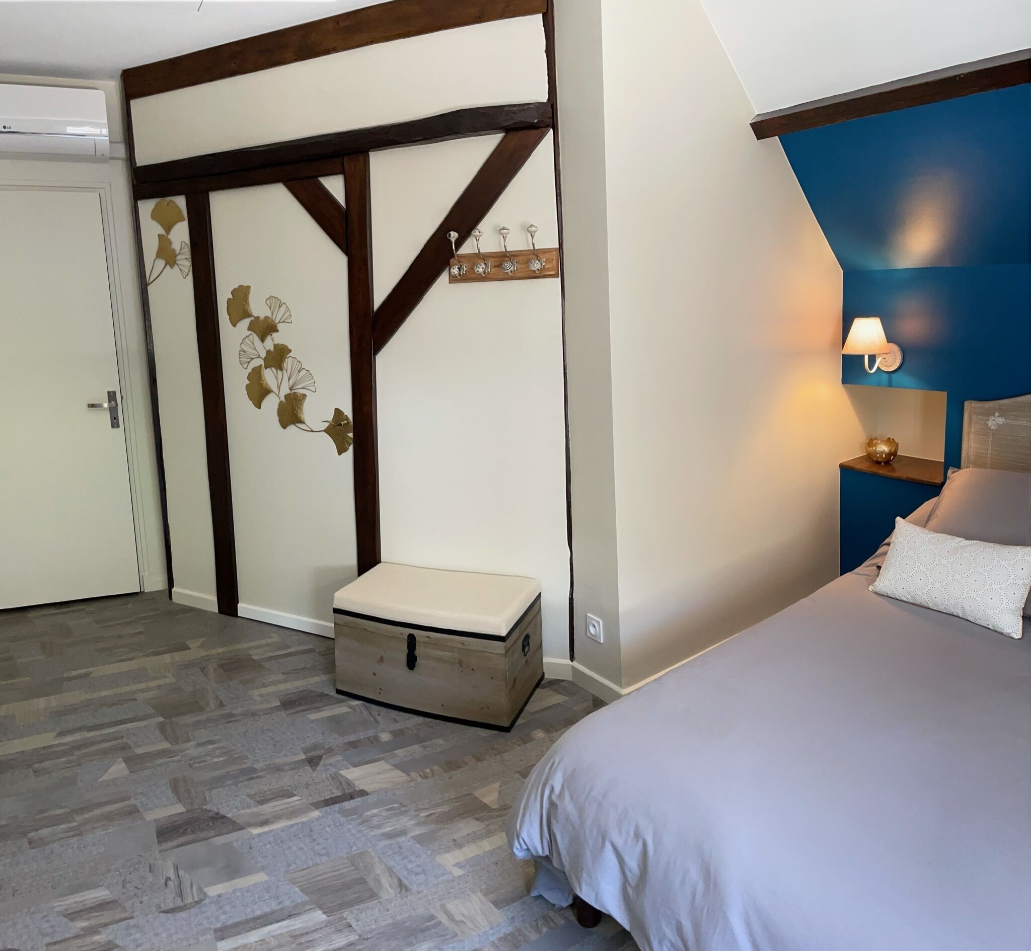 A bedroom with a bed, a nightstand, a dresser, and a wall with a decorative panel.