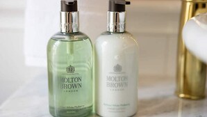 Deux flacons de crème pour les mains Molton Brown posés sur une surface en marbre.