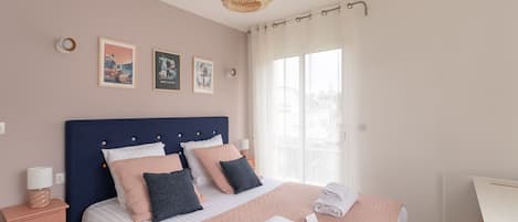 Un dormitorio con cama, almohadas, una mesita de noche, lámpara, una silla y obras de arte en la pared.
