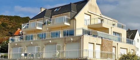 A multi-story building with balconies, a flat roof, and a chimney.