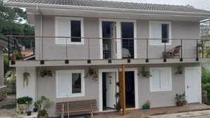 A two-story house with a balcony, potted plants, and a bench. - Suites Bela João e Maria (Campos do Jordão)
