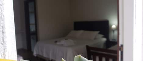 Quarto com cama, mesa de cabeceira e janela.