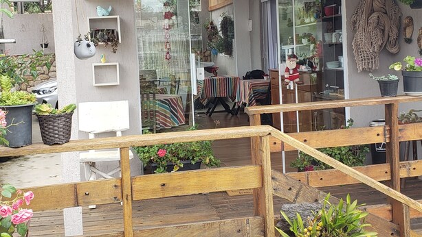 A wooden staircase leading to a shop with various hanging plants and shelves of items. - Suites Bela João e Maria (Campos do Jordão)