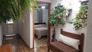 A bedroom with a bed, a wooden bench, and a wall-mounted plant with flowers. - Suites Bela João e Maria (Campos do Jordão)