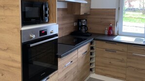 Une cuisine moderne dotée de meubles en bois, d’un four Bosch, d’un four à micro-ondes, d’une machine à café et d’un meuble à vin.