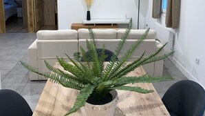 Un salon moderne avec une table à manger en bois, un canapé et un téléviseur fixé au mur.
