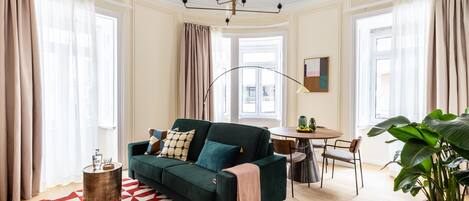 A modern living room with a green sofa, a round coffee table, and a red and white patterned rug.