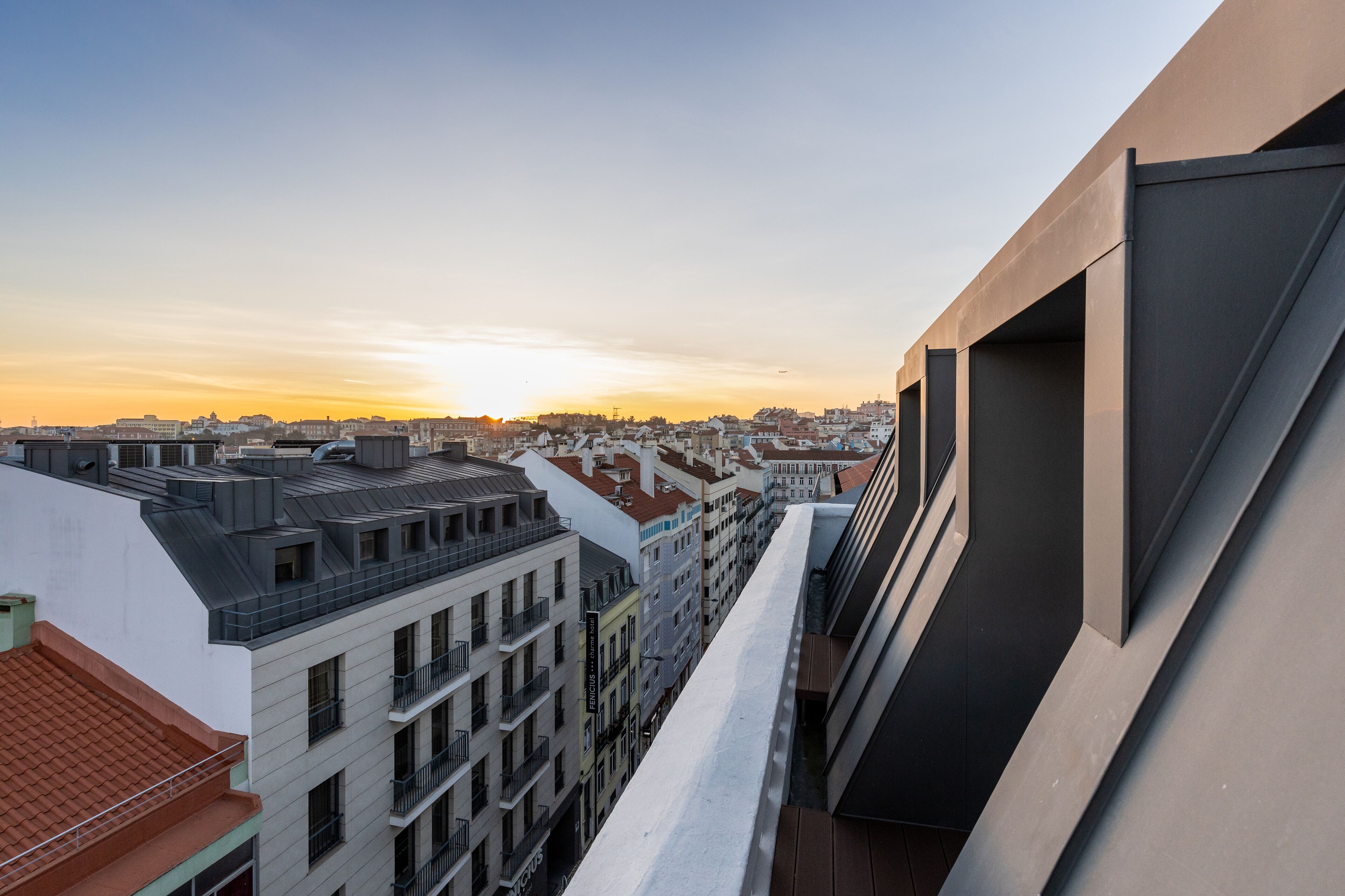 A high-rise building with multiple balconies and a view of the cityscape during sunset.