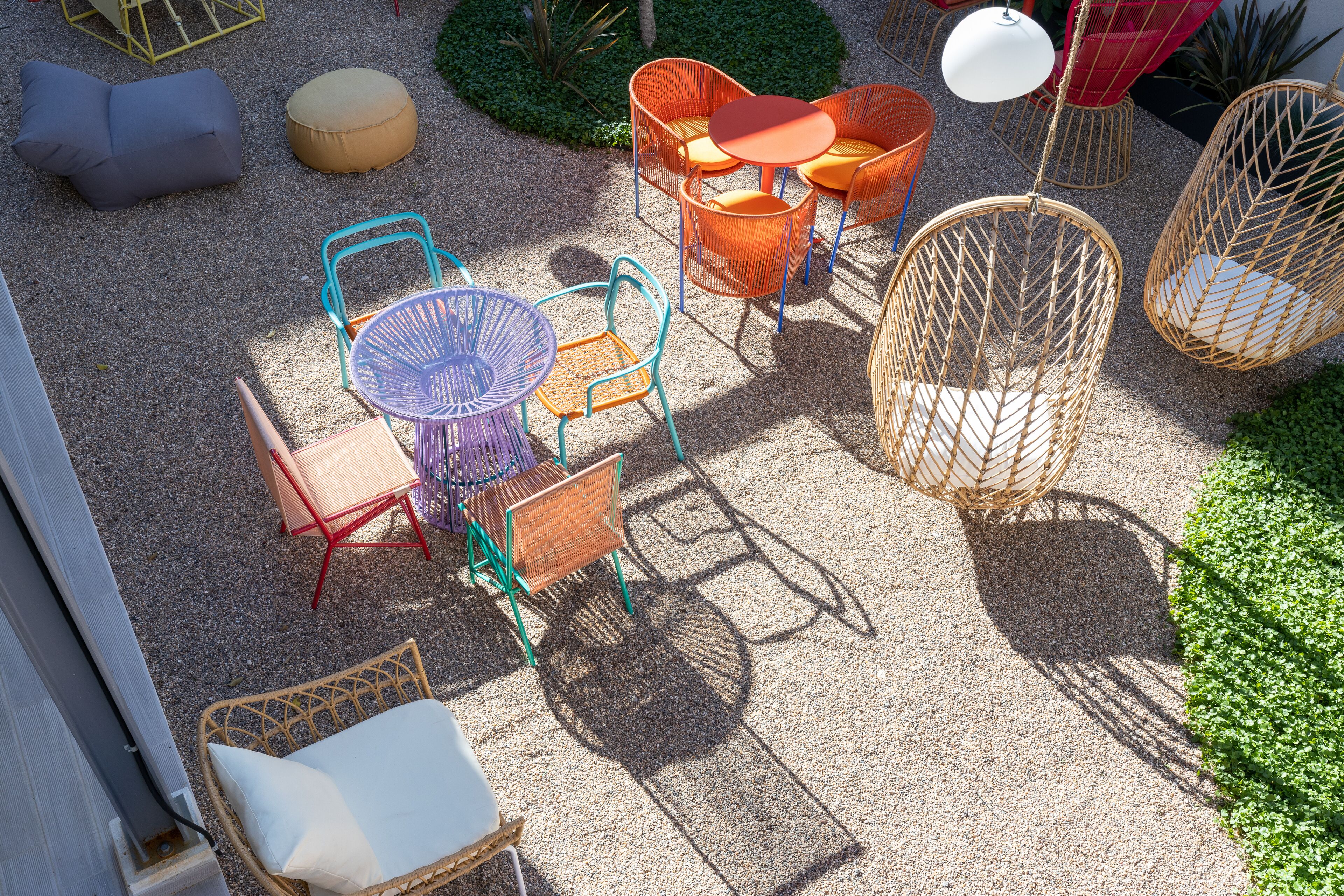Un espace extérieur aménagé avec différents types de chaises et de tables, entouré de verdure.