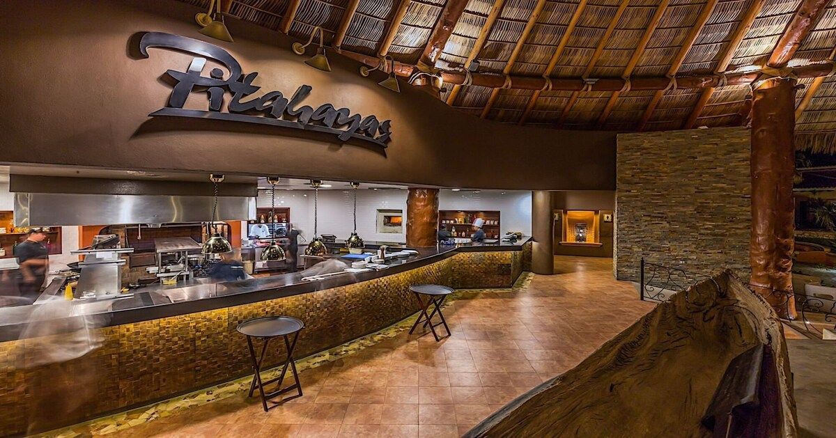 A restaurant interior with a bar area, stone accents, and a thatched roof.