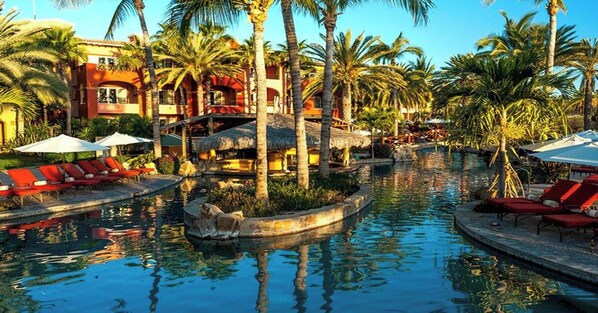 A pool area with lounge chairs and palm trees.