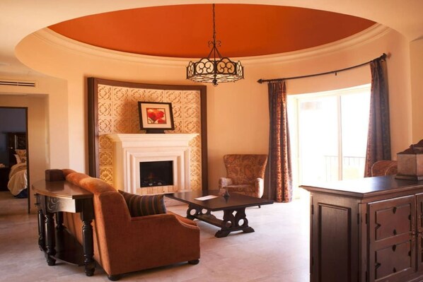 A room with a fireplace, a sofa, a chair, a table, and a cabinet.