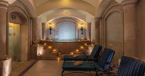 A spa area with stone columns, a central seating area with chairs, and wall-mounted lights.