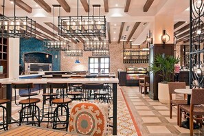 Un restaurant moderne doté d’un bar, d’un espace pour s’asseoir et d’une cuisine située à l’arrière.