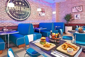 A restaurant interior with blue booths, tables, and a wall sign advertising hamburgers.