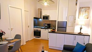 A compact living space with a dining area, kitchenette, and a sofa. - Cosy Apartment  37m2 in the heart of Natural Park of Pyrenees (Aulus-les-Bains)