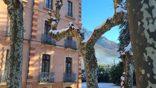 A multi-story building with balconies, surrounded by snow-covered trees. - Cosy Apartment  37m2 in the heart of Natural Park of Pyrenees (Aulus-les-Bains)