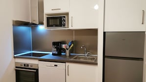 A compact kitchen with a microwave, coffee maker, sink, dishwasher, oven, and refrigerator. - Cosy Apartment  37m2 in the heart of Natural Park of Pyrenees (Aulus-les-Bains)