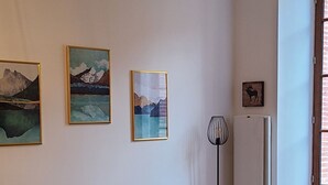 A living room with a dark sofa, a small white table, and three framed artworks on the wall. - Cosy Apartment  37m2 in the heart of Natural Park of Pyrenees (Aulus-les-Bains)