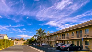 A parking lot with several cars, a building with balconies, and a clear blue sky. - New Star Inn. El Monte, CA - Los Angeles (El Monte)