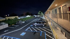 A parking lot with marked handicapped spaces, a row of parked cars, and a building with a balcony on the right. - New Star Inn. El Monte, CA - Los Angeles (El Monte)