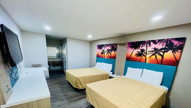 A hotel room with two beds, a desk, and a TV. - New Star Inn. El Monte, CA - Los Angeles (El Monte)