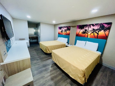 A hotel room with two beds, a desk, and a TV.